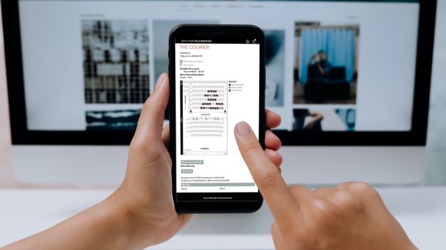 photo of a person using their smartphone to purchase in-theater, reserved tickets